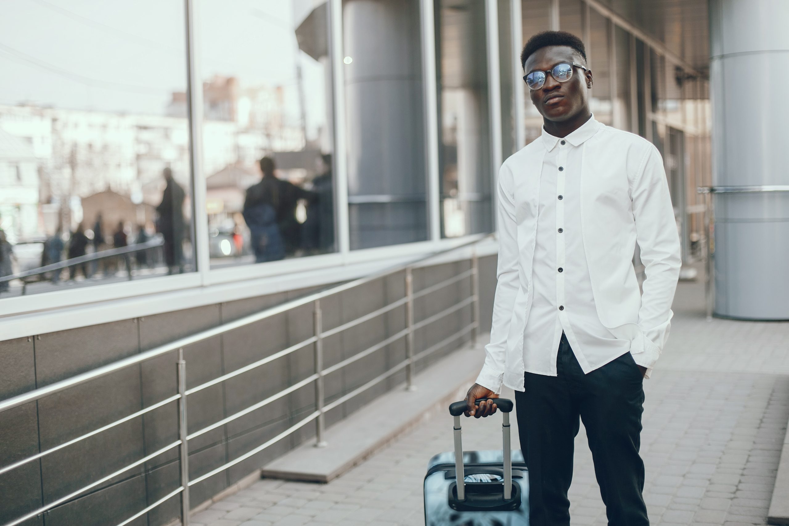 black-man-wearing-a-white-shirt-carrying-a-suitcase-in a city.